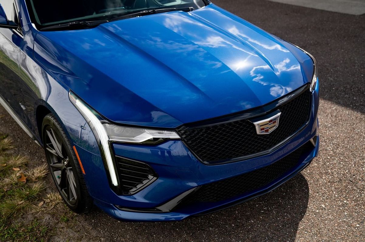 a blue cadillac is parked on the side of the road .