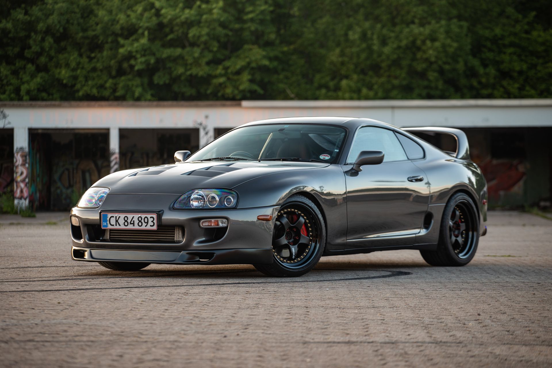 a toyota supra is parked in front of a garage .